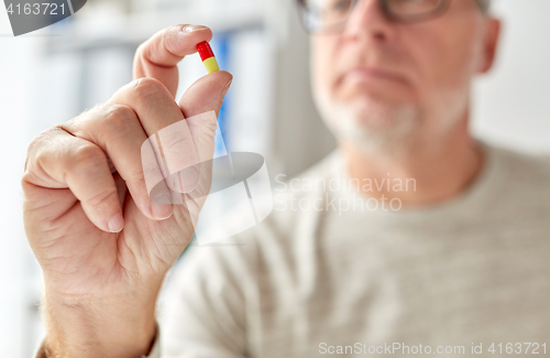 Image of close up of old man hand with pill