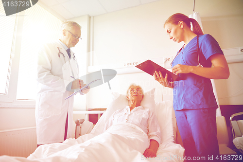 Image of doctor and nurse visiting senior woman at hospital