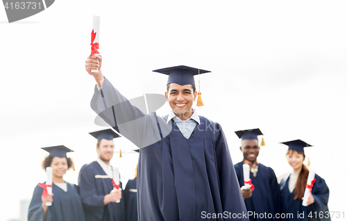 Image of happy students in mortar boards with diplomas