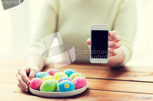 Image of close up of hands with easter eggs and smartphone