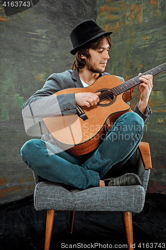 Image of Cool guy with hat playing guitar on gray background