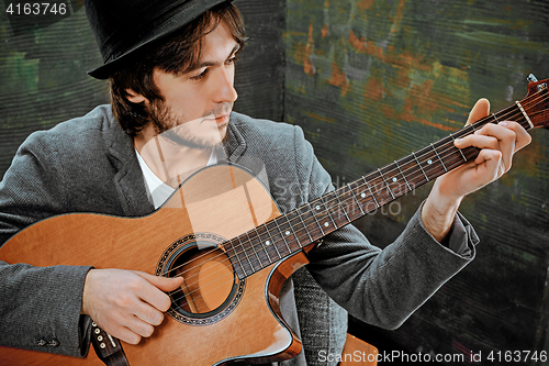 Image of Cool guy with hat playing guitar on gray background