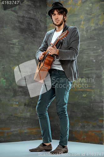 Image of Cool guy with hat playing guitar on gray background
