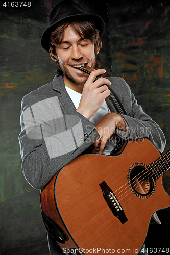 Image of Cool guy with hat playing guitar on gray background