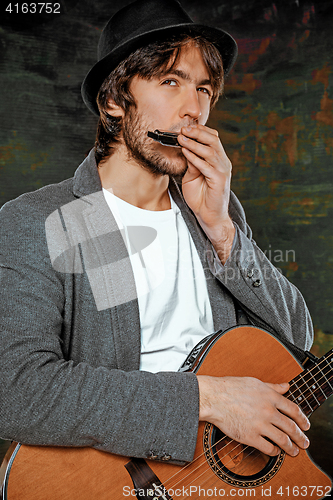 Image of Cool guy with hat playing guitar on gray background