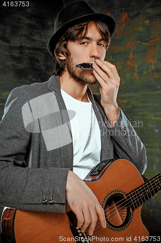 Image of Cool guy with hat playing guitar on gray background