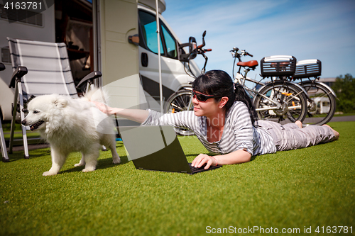 Image of Woman on the grass with a dog looking at a laptop