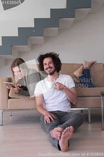 Image of couple relaxing at  home with tablet computers