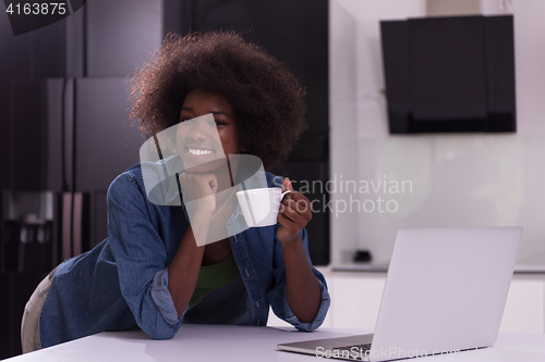 Image of smiling black woman in modern kitchen