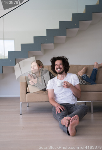 Image of couple relaxing at  home with tablet computers