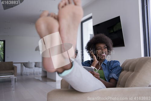 Image of African american woman at home in chair with tablet and head pho