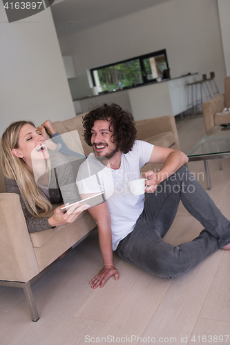 Image of couple relaxing at  home with tablet computers