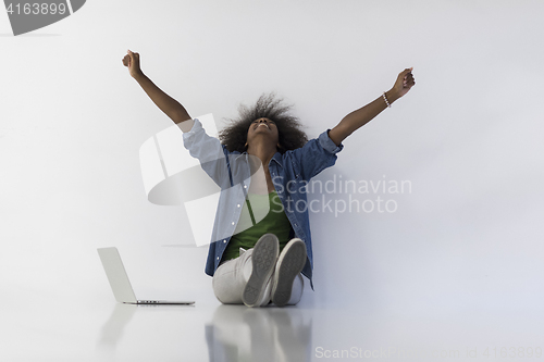 Image of african american woman sitting on floor with laptop