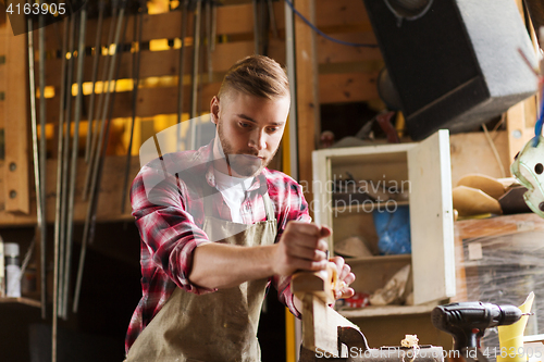 Image of carpenter working with plane and wood at workshop