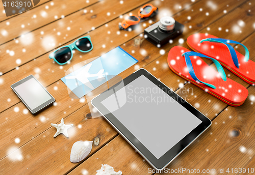 Image of tablet pc, airplane ticket and beach stuff