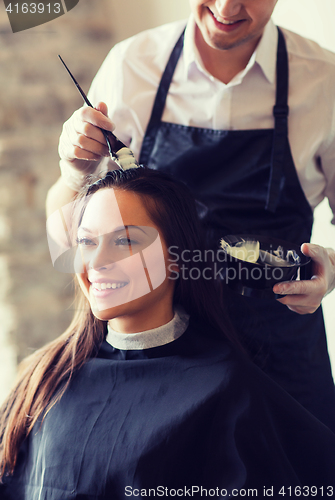 Image of happy woman with stylist coloring hair at salon