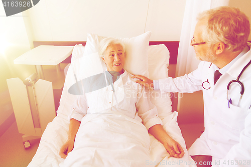 Image of doctor visiting senior woman at hospital ward