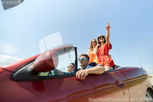 Image of happy friends driving in cabriolet car at country