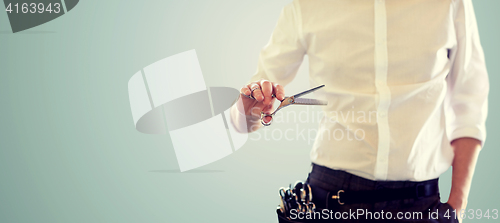 Image of close up of male stylist with scissors over blue