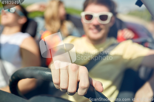 Image of happy friends driving in convertible car