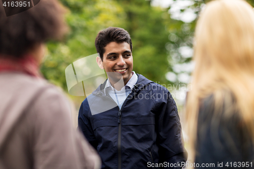 Image of happy friends walking along autumn park