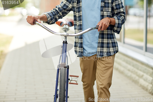 Image of close up of man with bicycle walking along city