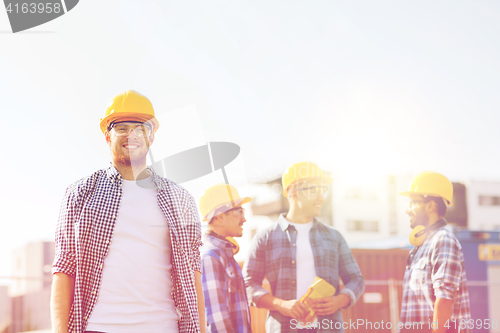 Image of group of smiling builders in hardhats outdoors