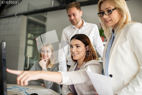 Image of happy creative team with computer in office