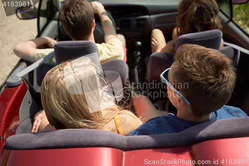 Image of happy friends driving in convertible car at summer