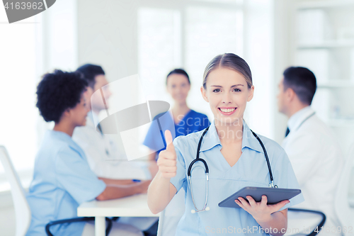 Image of happy doctor with tablet pc over team at clinic