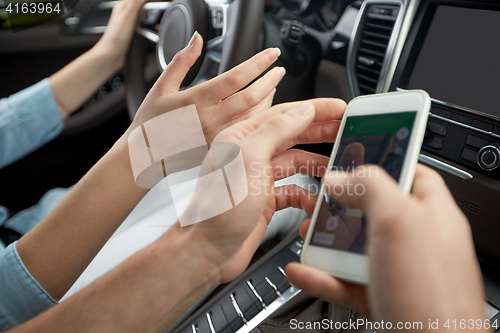 Image of happy man and woman with smartphone driving in car