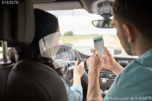 Image of happy man and woman with smartphone driving in car