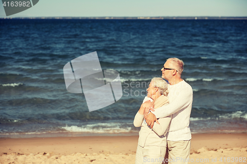 Image of happy senior couple hugging on summer beach