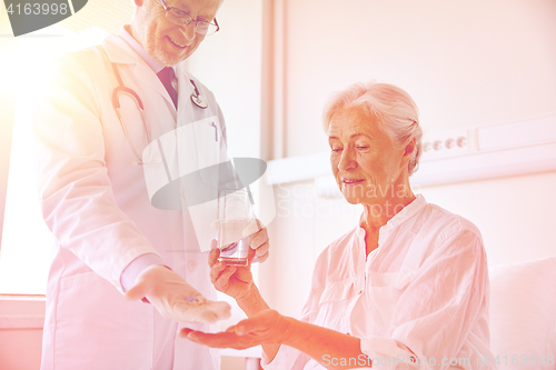 Image of doctor giving medicine to senior woman at hospital