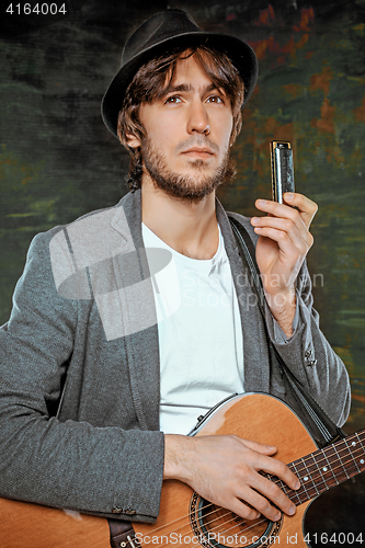 Image of Cool guy with hat playing guitar on gray background