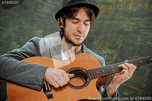 Image of Cool guy with hat playing guitar on gray background