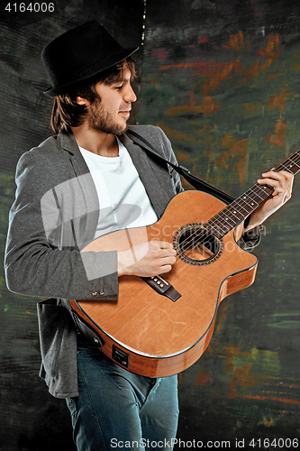 Image of Cool guy with hat playing guitar on gray background