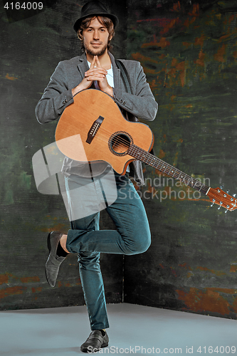 Image of Cool guy standing with guitar on gray background