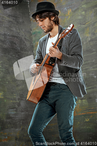 Image of Cool guy with hat playing guitar on gray background