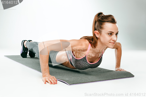 Image of Beautiful slim brunette doing some push ups a the gym