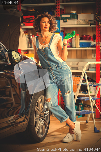 Image of smiling woman car mechanic with the instructions in blue overall