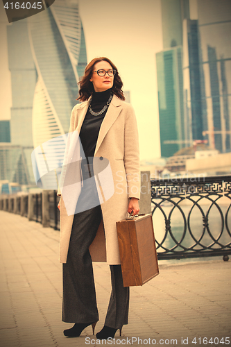 Image of beautiful smiling businesswoman in a light coat