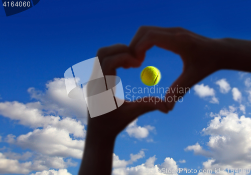 Image of tennis ball midair with cloudy sky above 