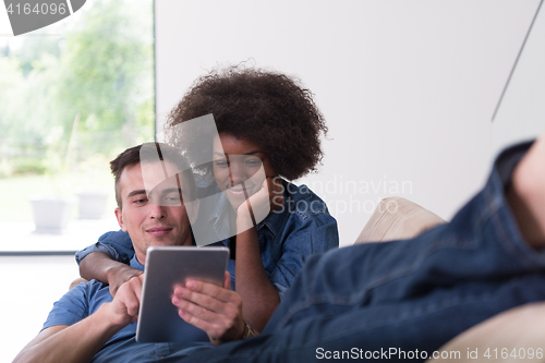 Image of multiethnic couple relaxing at  home with tablet computers