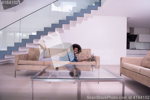 Image of African American woman using laptop on sofa