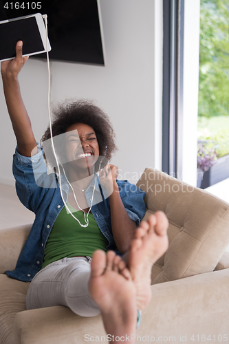 Image of African american woman at home in chair with tablet and head pho