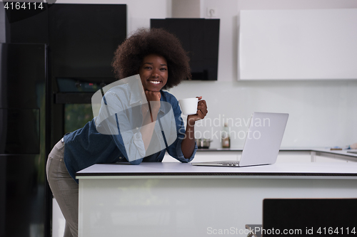 Image of smiling black woman in modern kitchen