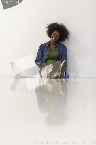 Image of african american woman sitting on floor with laptop