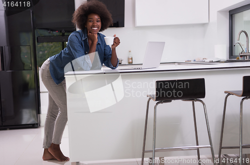 Image of smiling black woman in modern kitchen