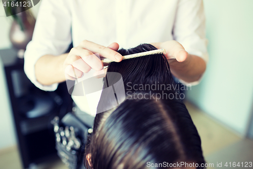 Image of male stylist hands combing wet hair at salon